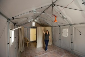 Roberta Russo, a communication officer for the UNHCR, shows a new a pre-fabricated house is to serve as an alternative to tents for refugees that designed by the Swedish furniture manufacturer IKEA for UNHCR, in Beirut, Lebanon, Wednesday July 24, 2013. A housing unit designed for the United Nations' refugee agency to offer shelter for those, fleeing conflict has become the latest source of friction between Lebanese politicians and aid organizations trying to manage the massive number of Syrian refugees in the country. Lebanon's refusal to set up any kind of organized accommodation for tens of thousands of Syrians, including refugee camps. (AP Photo/Hussein Malla)